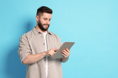 Photo of Man using tablet on light blue background, space for text
