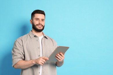 Photo of Man using tablet on light blue background, space for text