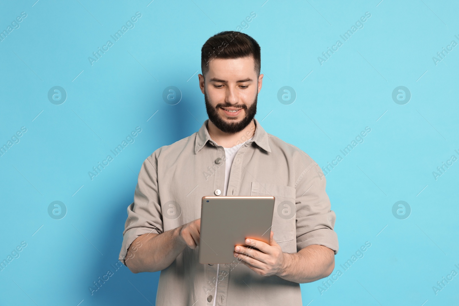 Man using tablet on light blue background Photo of Man using tablet on light blue background