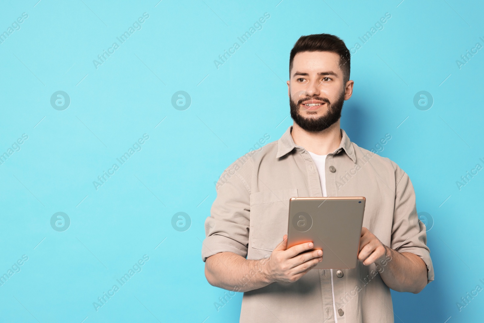 Man using tablet on light blue background, space for text Photo of Man using tablet on light blue background, space for text
