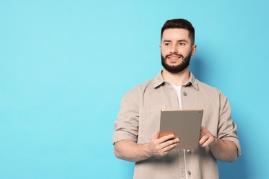 Photo of Man using tablet on light blue background, space for text