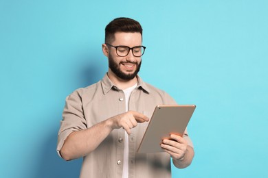Photo of Man using tablet on light blue background