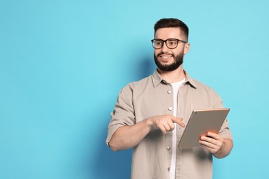 Photo of Man using tablet on light blue background, space for text
