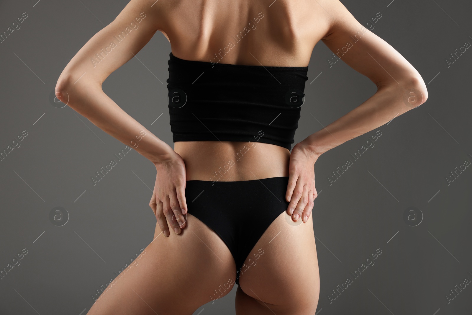Woman with perfect slim body on grey background, back view Photo of Woman with perfect slim body on grey background, back view