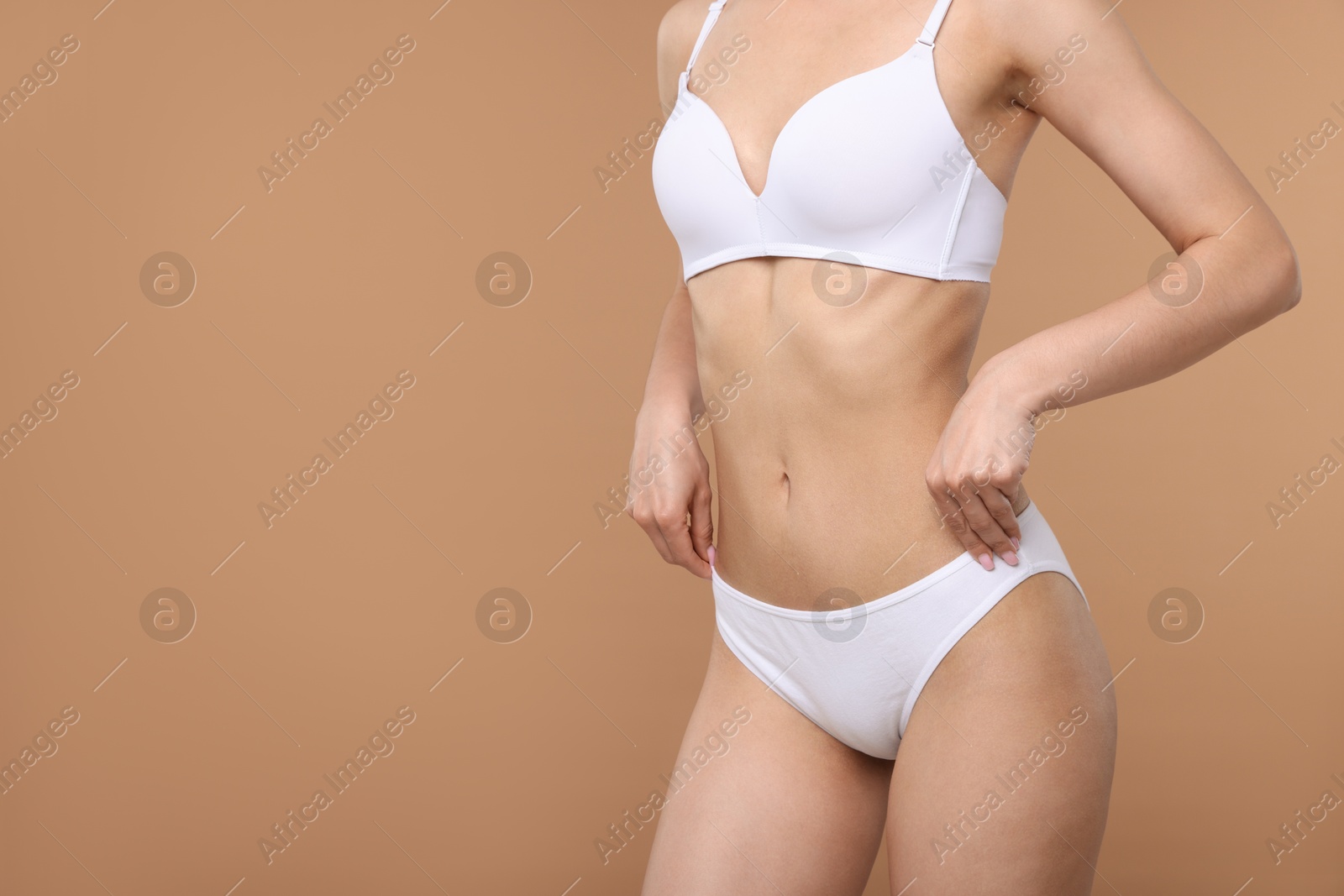 Woman with perfect slim body on beige background, closeup. Space for text Photo of Woman with perfect slim body on beige background, closeup. Space for text
