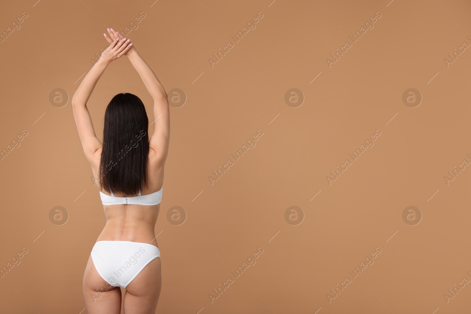 Woman with perfect slim body on beige background, back view. Space for text Photo of Woman with perfect slim body on beige background, back view. Space for text