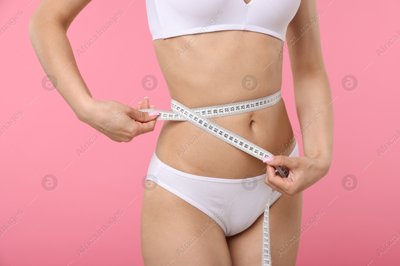 Woman with slim body and measuring tape on pink background, closeup Photo of Woman with slim body and measuring tape on pink background, closeup