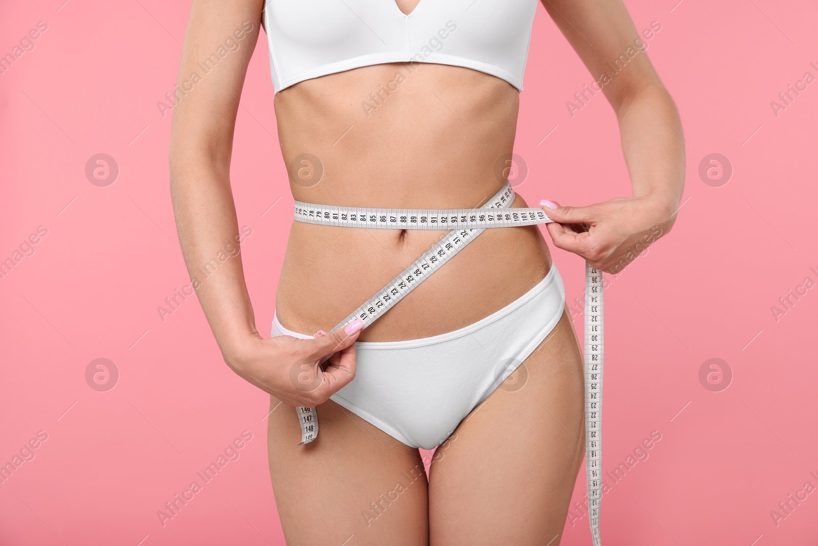 Woman with slim body and measuring tape on pink background, closeup Photo of Woman with slim body and measuring tape on pink background, closeup