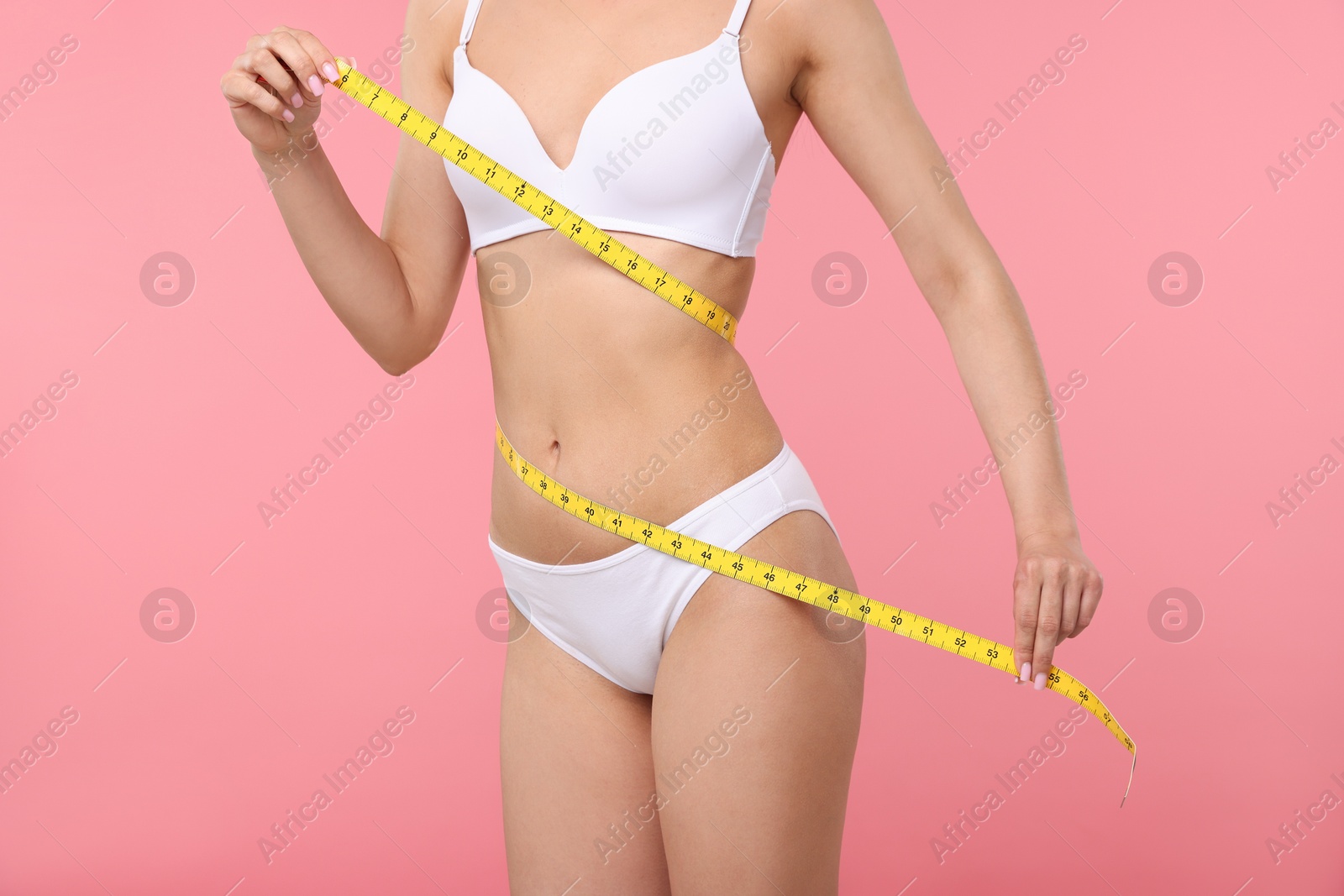 Woman with slim body and measuring tape on pink background, closeup Photo of Woman with slim body and measuring tape on pink background, closeup