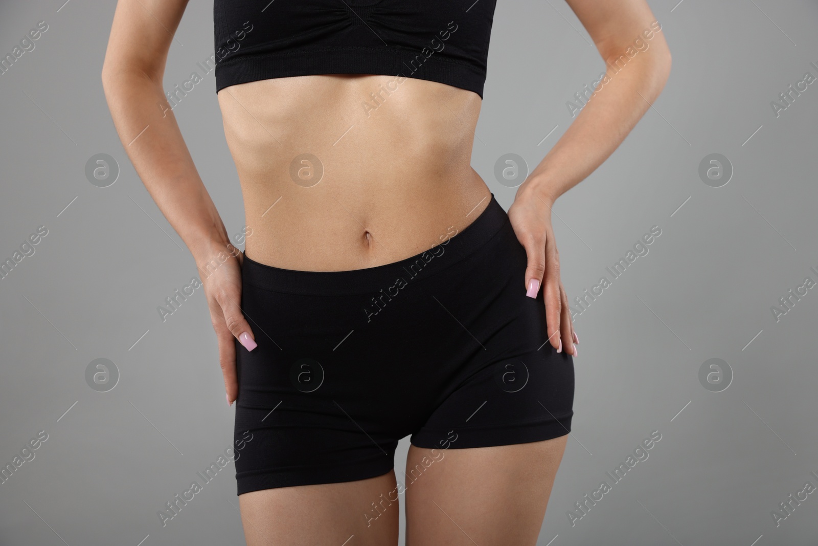 Woman with perfect slim body on gray background, closeup Photo of Woman with perfect slim body on gray background, closeup