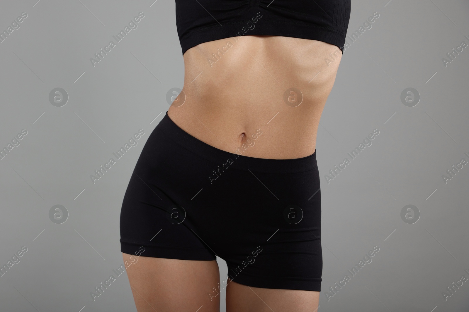 Woman with perfect slim body on gray background, closeup Photo of Woman with perfect slim body on gray background, closeup
