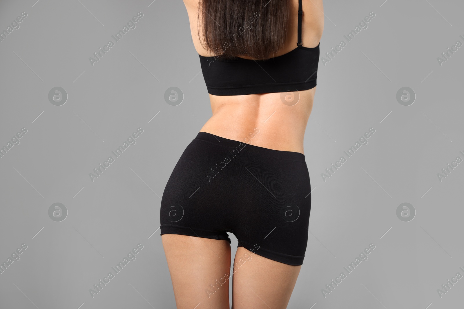 Woman with perfect slim body on gray background, closeup Photo of Woman with perfect slim body on gray background, closeup