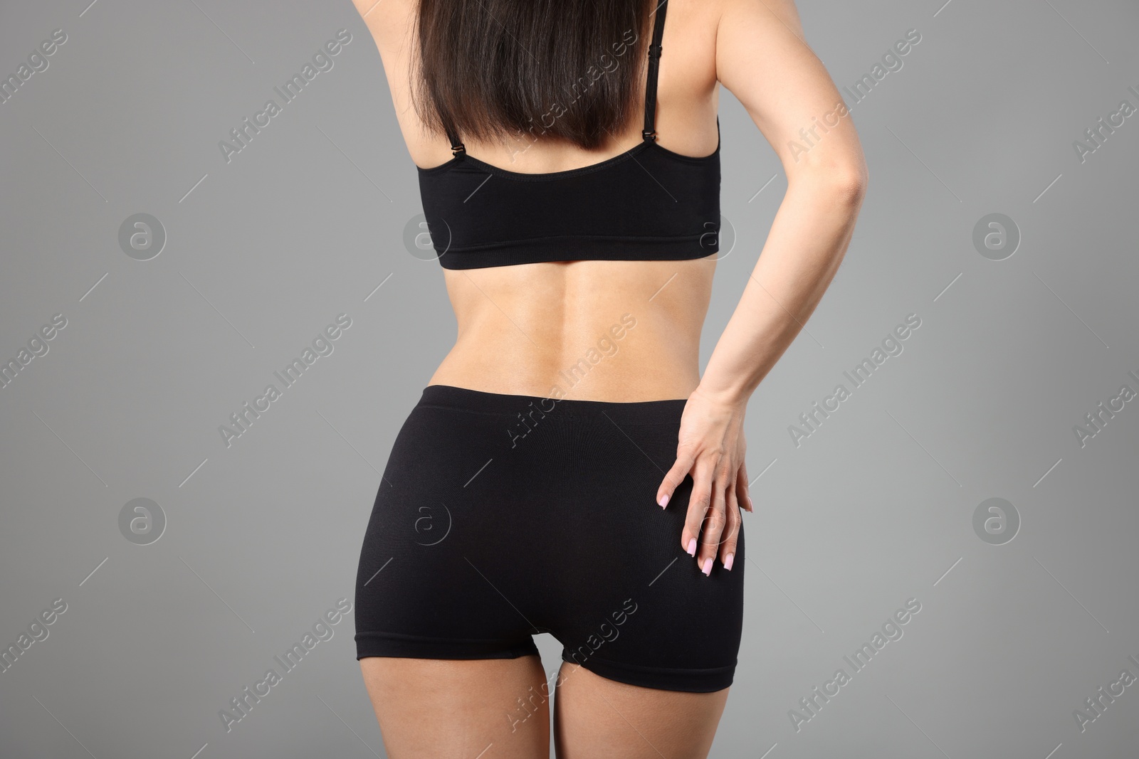 Woman with perfect slim body on gray background, closeup Photo of Woman with perfect slim body on gray background, closeup
