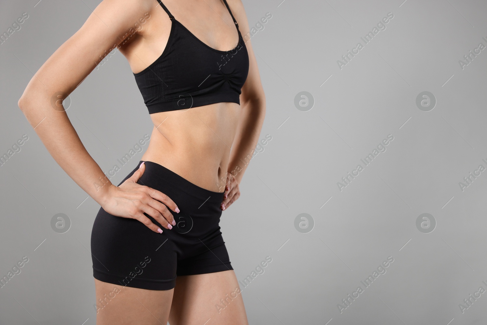 Woman with perfect slim body on gray background, closeup. Space for text Photo of Woman with perfect slim body on gray background, closeup. Space for text