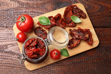 Photo of Tasty sun dried tomatoes and fresh vegetables on wooden table, top view