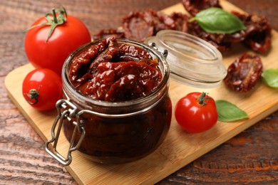 Photo of Tasty sun dried tomatoes and fresh vegetables on wooden table, closeup