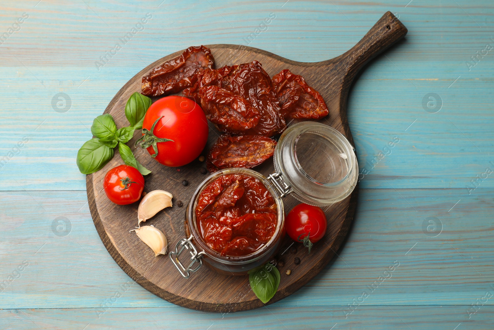 Tasty sun dried tomatoes, fresh vegetables and peppercorns on light blue wooden table, top view Photo of Tasty sun dried tomatoes, fresh vegetables and peppercorns on light blue wooden table, top view