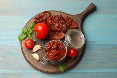 Photo of Tasty sun dried tomatoes, fresh vegetables and peppercorns on light blue wooden table, top view