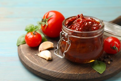Photo of Tasty sun dried tomatoes, fresh vegetables and peppercorns on light blue wooden table, closeup