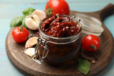 Photo of Tasty sun dried tomatoes, fresh vegetables and peppercorns on light blue wooden table, closeup