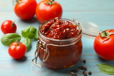 Photo of Tasty sun dried tomatoes, fresh vegetables and peppercorns on wooden table, closeup