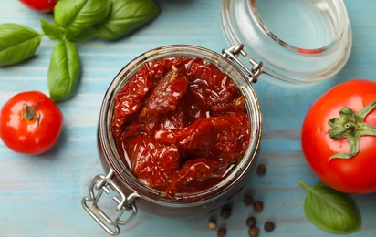 Photo of Tasty sun dried tomatoes, fresh vegetables and peppercorns on light blue wooden table, top view