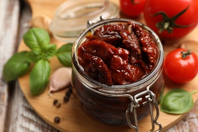Photo of Tasty sun dried tomatoes, fresh vegetables and peppercorns on wooden table, closeup