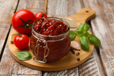 Photo of Tasty sun dried tomatoes, fresh vegetables and peppercorns on wooden table, closeup