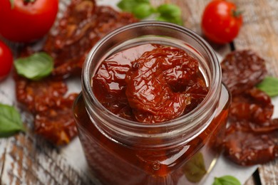 Photo of Tasty sun dried tomatoes and fresh vegetables on wooden table, closeup