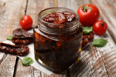 Photo of Tasty sun dried tomatoes and fresh vegetables on wooden table, closeup