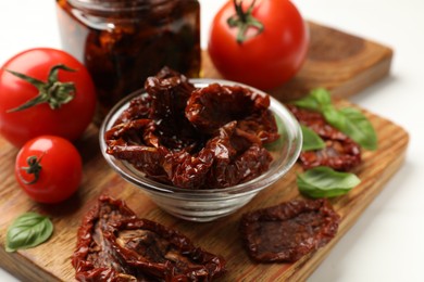 Photo of Tasty sun dried tomatoes and fresh vegetables on white table, closeup