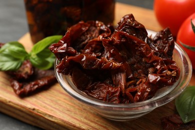 Photo of Tasty sun dried tomatoes and fresh vegetables on black table, closeup