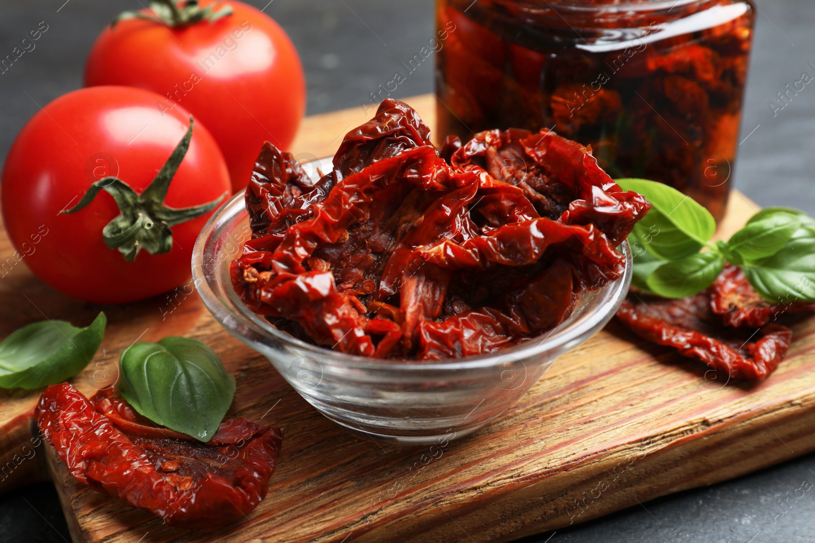 Tasty sun dried tomatoes and fresh vegetables on black table, closeup Photo of Tasty sun dried tomatoes and fresh vegetables on black table, closeup