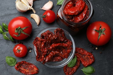 Photo of Tasty sun dried tomatoes, fresh vegetables and peppercorns on black table, flat lay