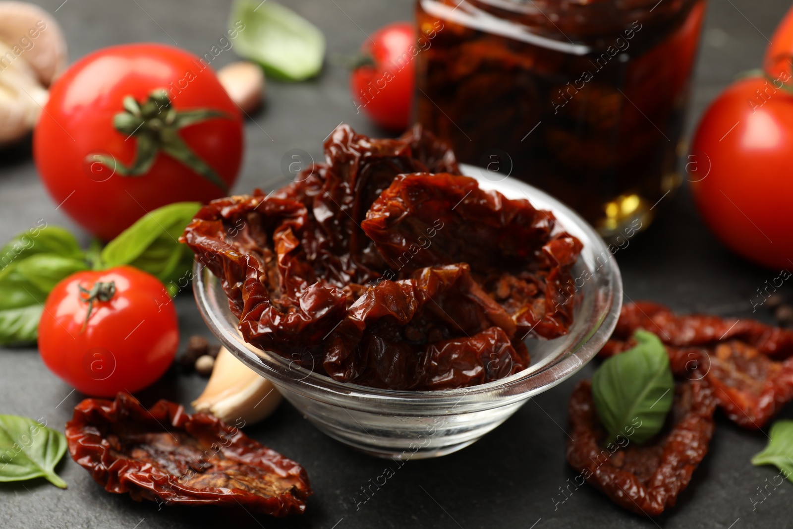 Tasty sun dried tomatoes and fresh vegetables on black table, closeup Photo of Tasty sun dried tomatoes and fresh vegetables on black table, closeup