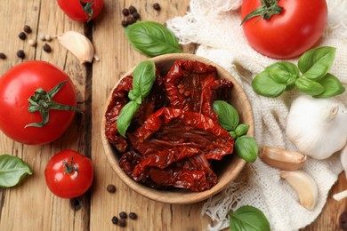 Photo of Tasty sun dried tomatoes, fresh vegetables and peppercorns on wooden table, flat lay