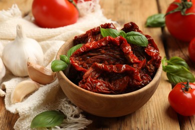Photo of Tasty sun dried tomatoes and fresh vegetables on wooden table, closeup