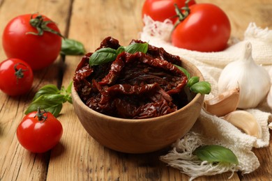 Photo of Tasty sun dried tomatoes and fresh vegetables on wooden table, closeup