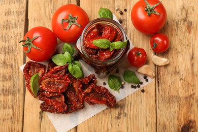 Photo of Tasty sun dried tomatoes, fresh vegetables and peppercorns on wooden table, flat lay