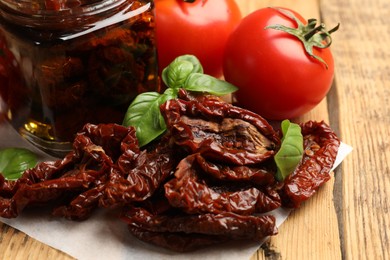 Photo of Tasty sun dried tomatoes and fresh vegetables on wooden table, closeup