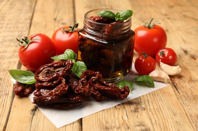 Photo of Tasty sun dried tomatoes and fresh vegetables on wooden table, closeup