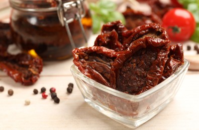 Photo of Tasty sun dried tomatoes, fresh vegetables and peppercorns on light wooden table, closeup