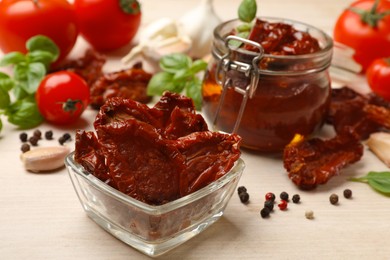 Photo of Tasty sun dried tomatoes, fresh vegetables and peppercorns on light wooden table, closeup
