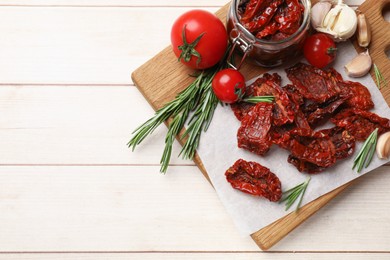 Photo of Tasty sun dried tomatoes and fresh vegetables on light wooden table, top view. Space for text
