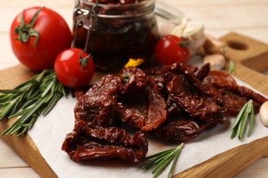 Photo of Tasty sun dried tomatoes and fresh vegetables on light wooden table, closeup