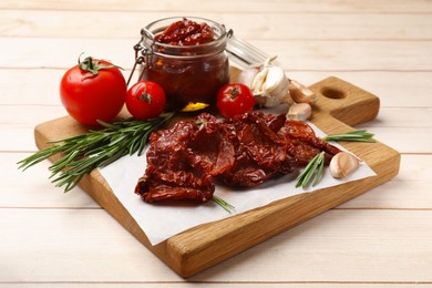 Photo of Tasty sun dried tomatoes and fresh vegetables on light wooden table, closeup