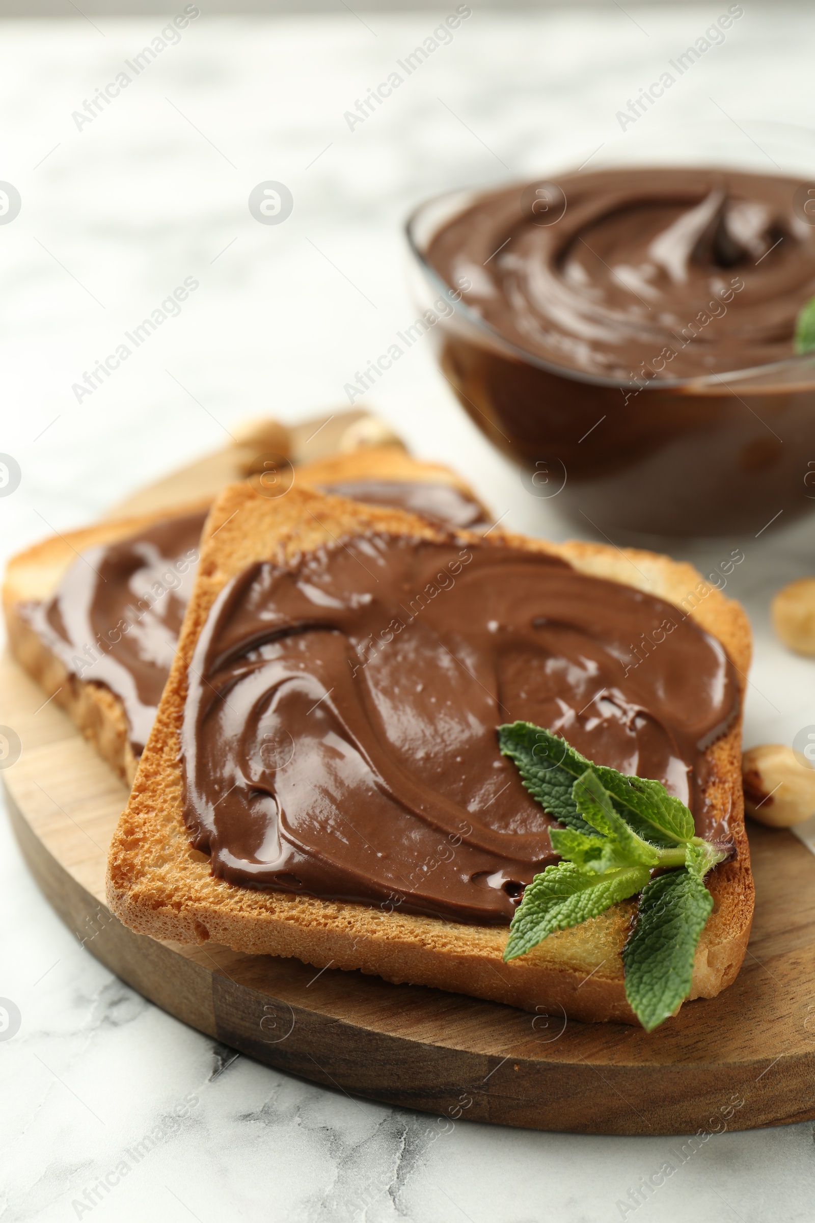 Tasty chocolate spread with mint and hazelnuts on white marble table, closeup Photo of Tasty chocolate spread with mint and hazelnuts on white marble table, closeup