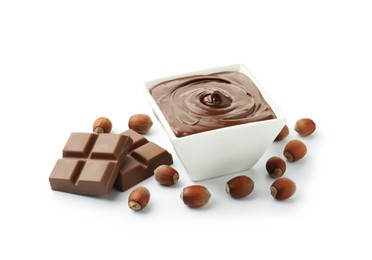 Photo of Tasty chocolate spread, pieces and hazelnuts isolated on white