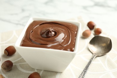 Photo of Tasty chocolate spread and hazelnuts on table, closeup