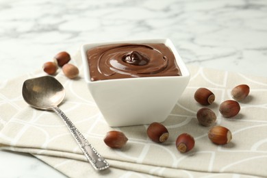 Photo of Tasty chocolate spread and hazelnuts on table, closeup